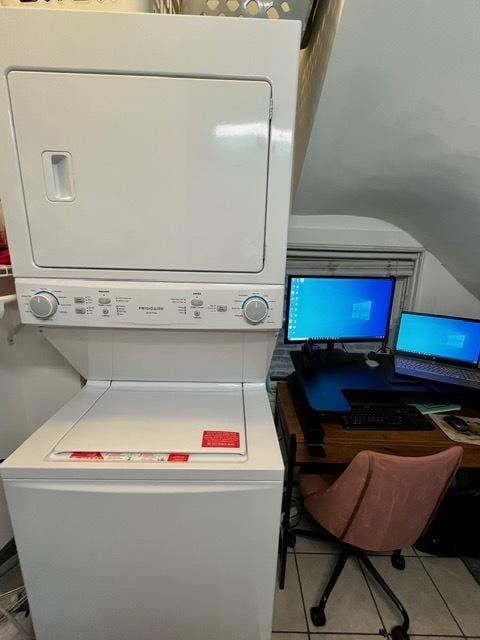 clothes washing area featuring stacked washer / dryer, laundry area, and tile patterned flooring