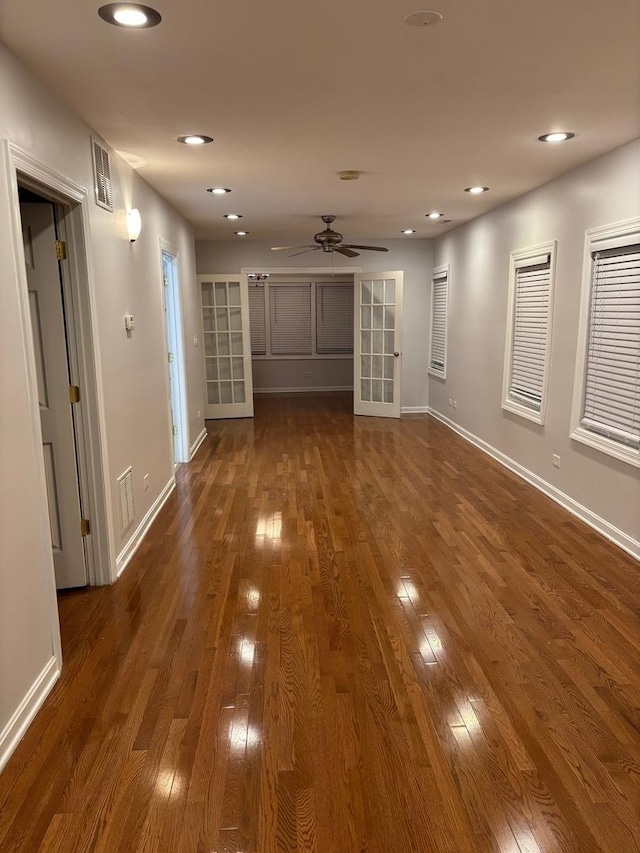 unfurnished living room with dark wood finished floors, baseboards, visible vents, and ceiling fan