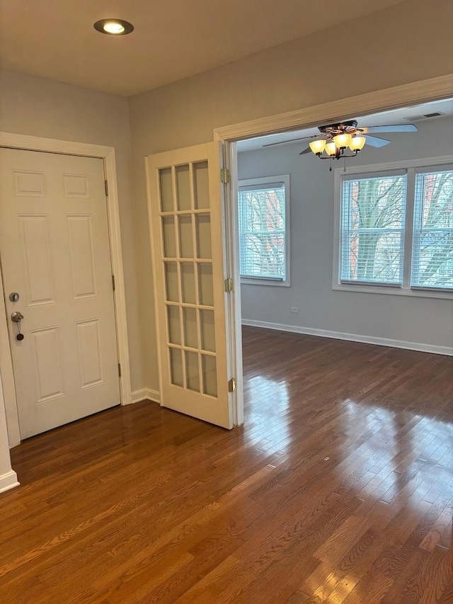 interior space with a ceiling fan, dark wood-style flooring, and baseboards
