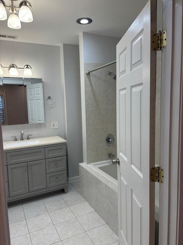 bathroom with visible vents, vanity, tiled shower / bath, tile patterned flooring, and a notable chandelier