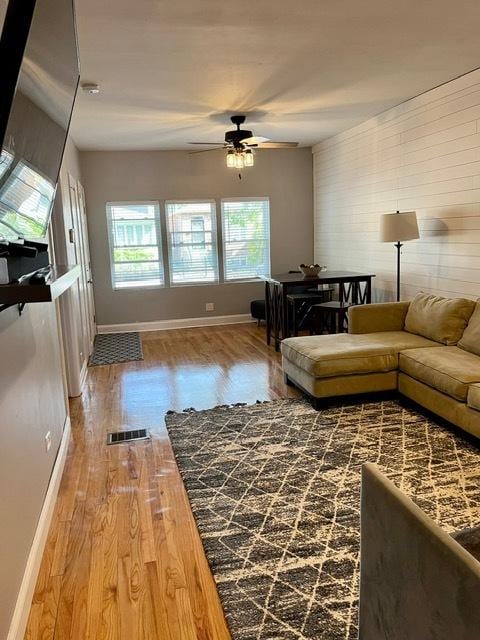 living area with visible vents, baseboards, ceiling fan, and wood finished floors