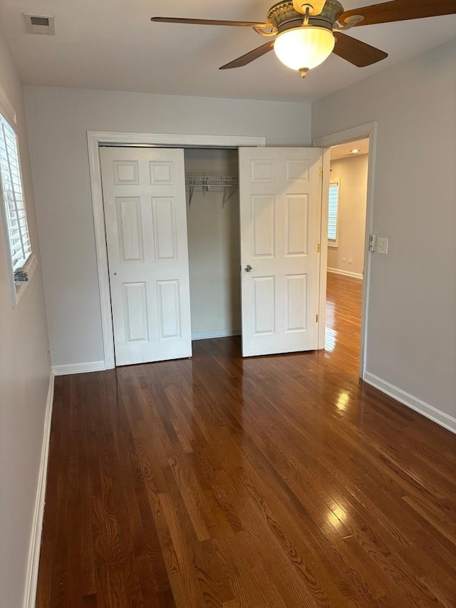 unfurnished bedroom featuring visible vents, a closet, baseboards, and wood finished floors