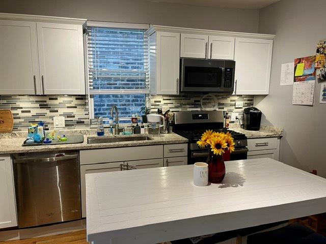 kitchen featuring a sink, white cabinetry, tasteful backsplash, and appliances with stainless steel finishes