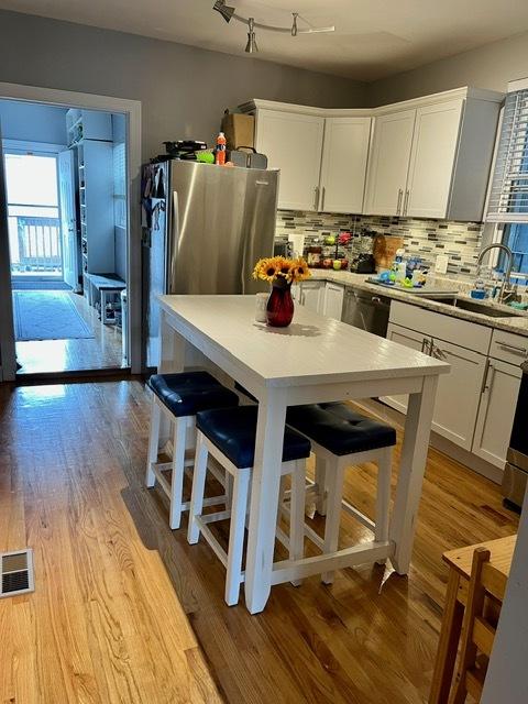 kitchen featuring light countertops, a sink, white cabinetry, tasteful backsplash, and wood finished floors
