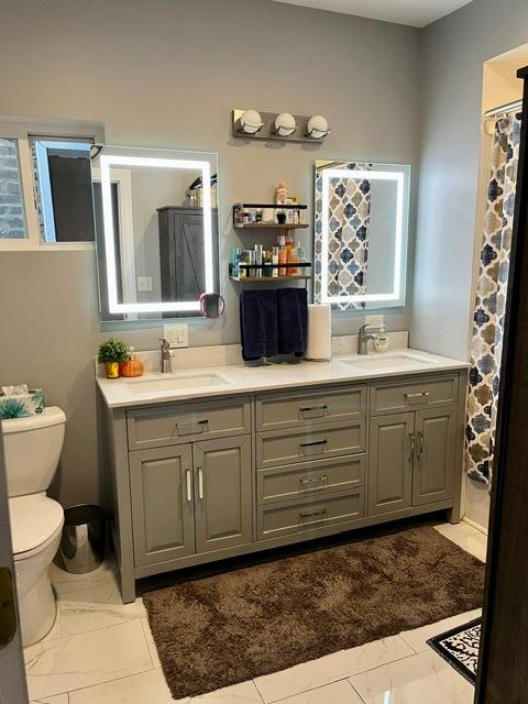 bathroom featuring double vanity, a sink, and toilet