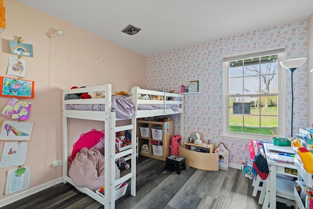bedroom with baseboards, wallpapered walls, and wood finished floors