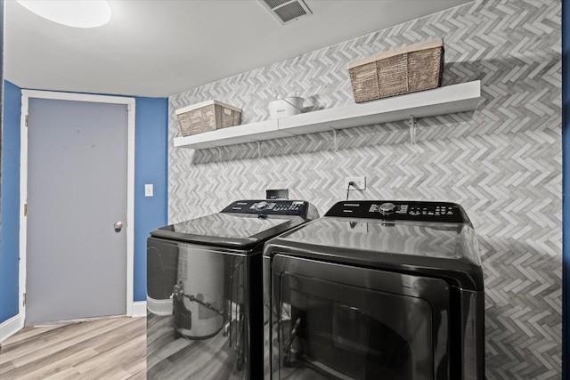 laundry area with laundry area, visible vents, wood finished floors, baseboards, and separate washer and dryer