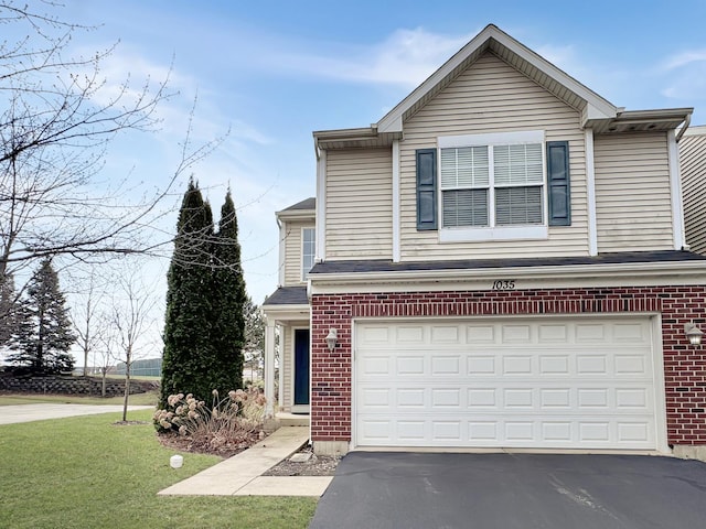 traditional home featuring an attached garage, aphalt driveway, a front lawn, and brick siding