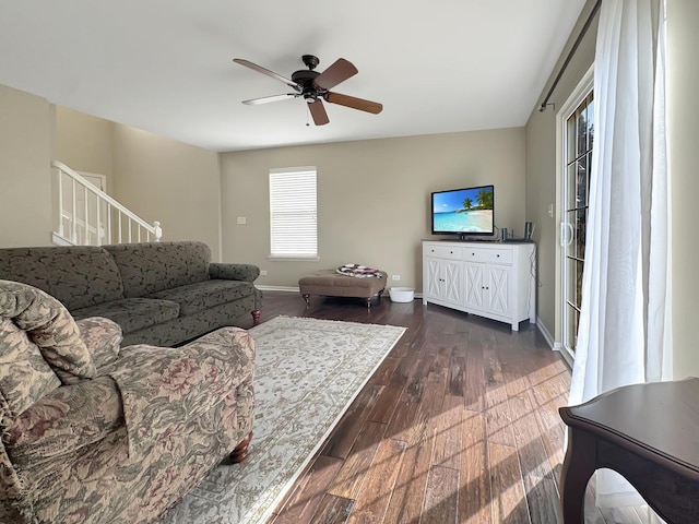 living area with dark wood-type flooring, ceiling fan, and baseboards