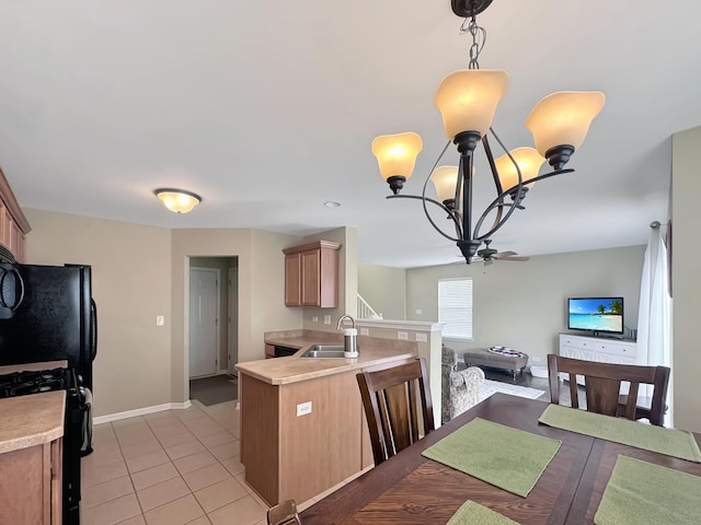 kitchen featuring light countertops, a sink, a notable chandelier, and black appliances