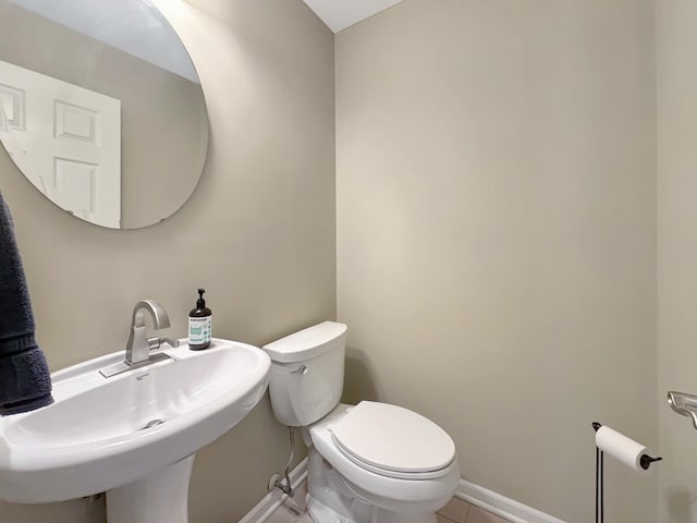 half bathroom featuring baseboards, a sink, toilet, and tile patterned flooring