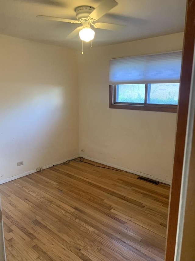 unfurnished room featuring baseboards, ceiling fan, wood finished floors, and visible vents