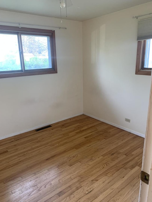 empty room with baseboards, wood finished floors, and visible vents