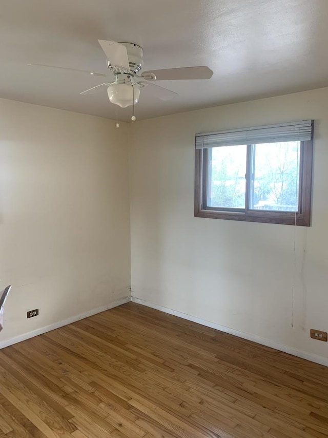 empty room with baseboards, ceiling fan, and wood finished floors