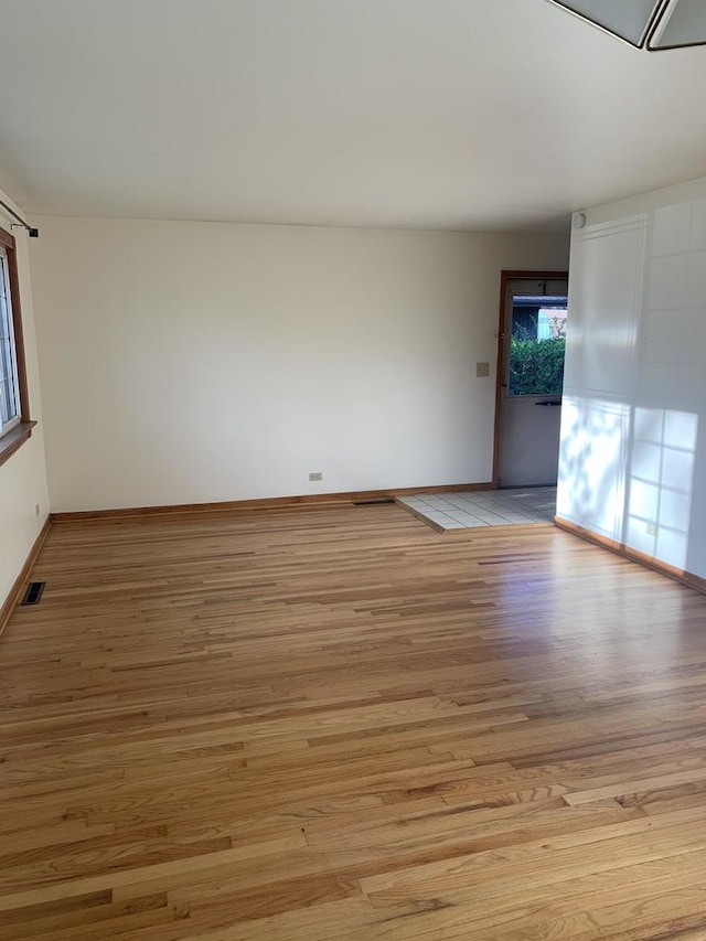 unfurnished room featuring baseboards, visible vents, and light wood-style floors