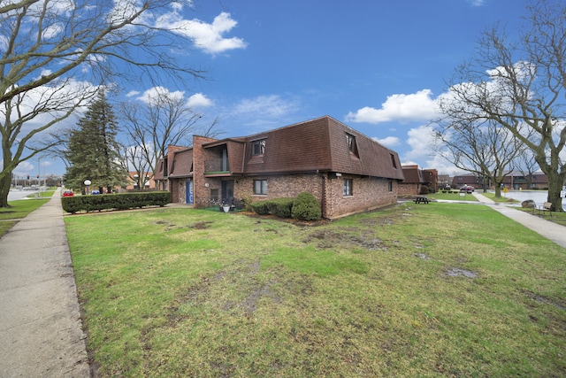 view of property exterior with a yard, brick siding, a shingled roof, and mansard roof
