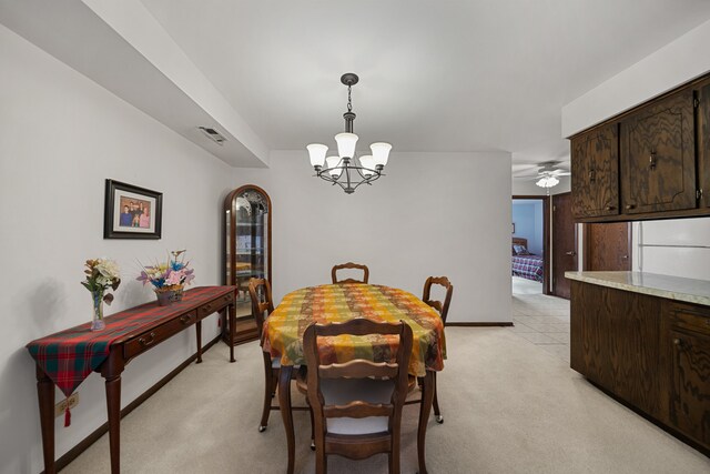 dining area featuring light colored carpet, visible vents, baseboards, and ceiling fan with notable chandelier