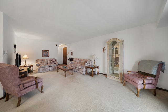 carpeted living room featuring baseboards and arched walkways
