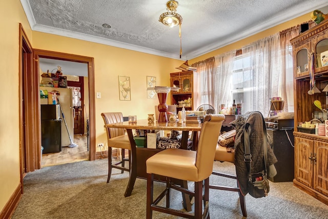 carpeted dining area with ornamental molding and a textured ceiling