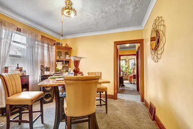 carpeted dining space featuring ornamental molding, baseboards, and a textured ceiling