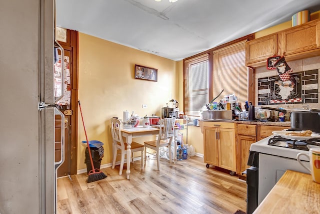 kitchen with tasteful backsplash, baseboards, white appliances, and light wood-style floors