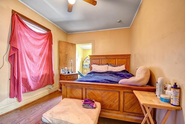 bedroom with crown molding, a ceiling fan, and wood finished floors