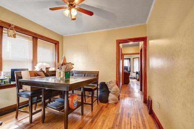 dining area featuring light wood finished floors, baseboards, crown molding, and ceiling fan