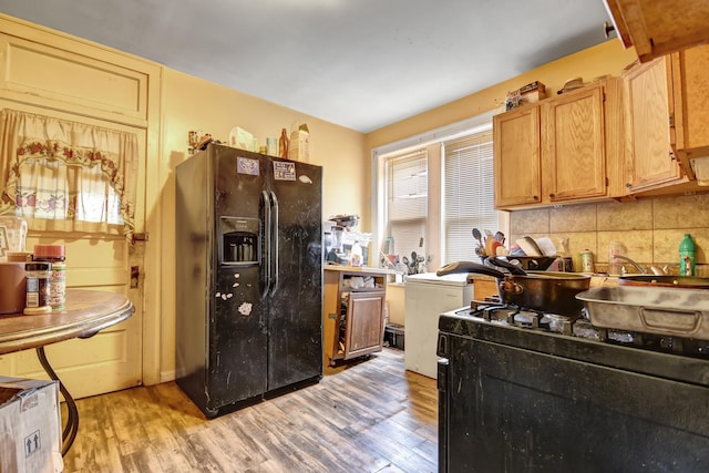 kitchen featuring light wood-style flooring, tasteful backsplash, and black appliances