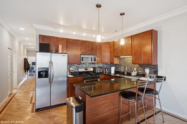 kitchen featuring crown molding, a peninsula, a sink, stainless steel appliances, and backsplash