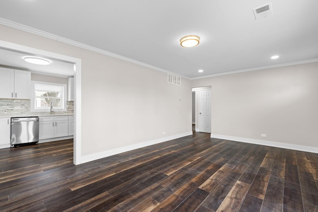 spare room with a sink, crown molding, baseboards, and visible vents