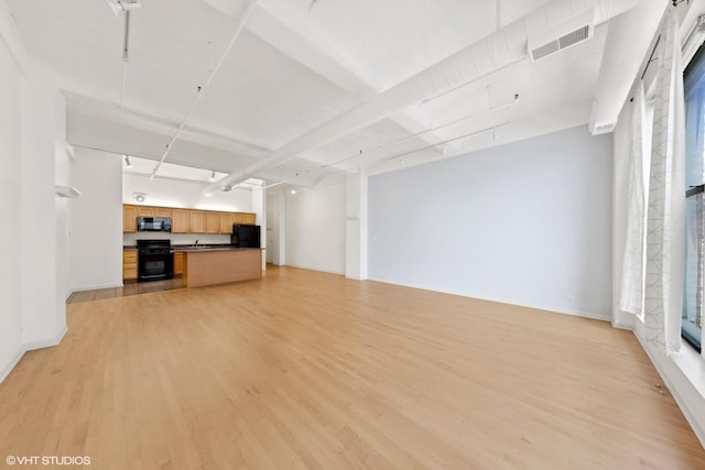 unfurnished living room featuring light wood-style floors, baseboards, and visible vents