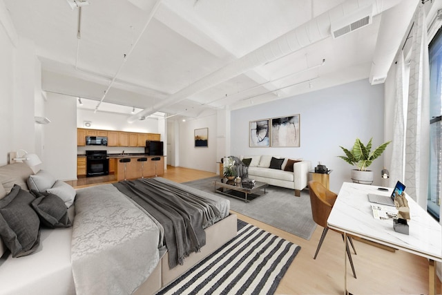 bedroom featuring black fridge, light wood-style floors, and visible vents