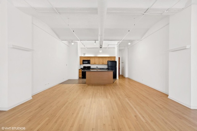kitchen with open floor plan, dark countertops, light wood-type flooring, black appliances, and rail lighting