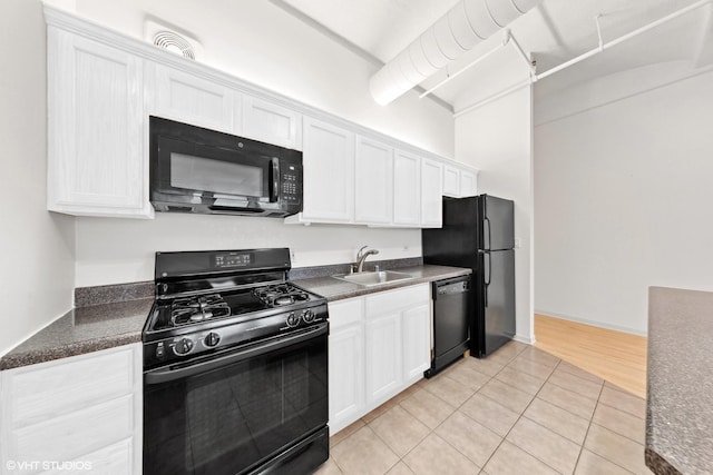 kitchen with light tile patterned floors, white cabinetry, dark countertops, black appliances, and a sink