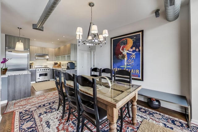 dining area with baseboards, wood finished floors, and an inviting chandelier