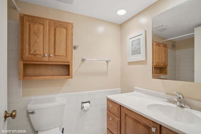 full bath with visible vents, toilet, tile walls, a shower, and a wainscoted wall