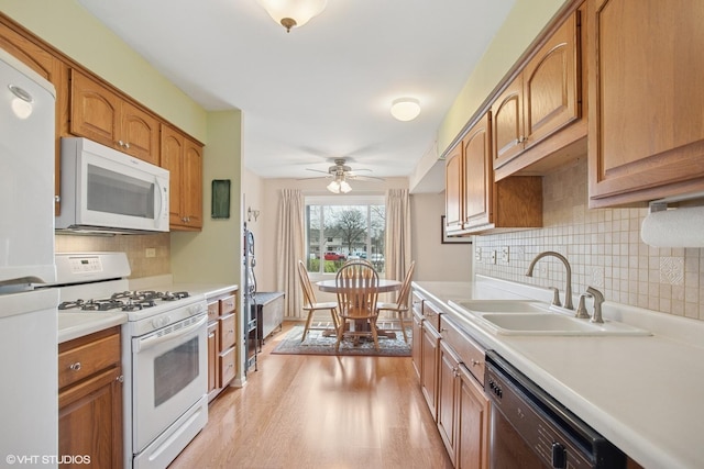 kitchen featuring a sink, light countertops, ceiling fan, white appliances, and light wood-style flooring