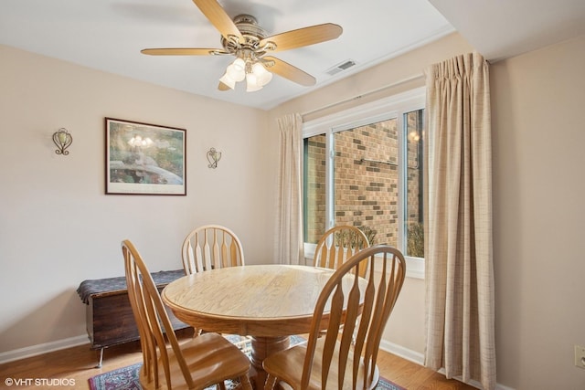 dining area featuring light wood-style flooring, baseboards, a ceiling fan, and visible vents