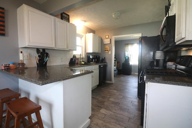 kitchen with white cabinetry, black appliances, and a peninsula