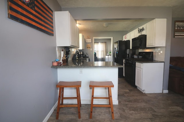 kitchen featuring white cabinets, black appliances, and a peninsula