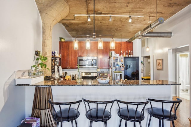 1070 W 15th St Unit 305, Chicago, IL 60608 - kitchen featuring appliances with stainless steel finishes, a peninsula, dark stone counters, wood finished floors, and a breakfast bar