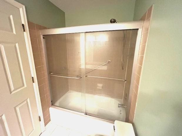 full bathroom with tile patterned flooring and bath / shower combo with glass door