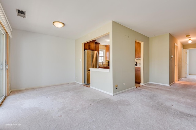 spare room with visible vents, light carpet, and baseboards
