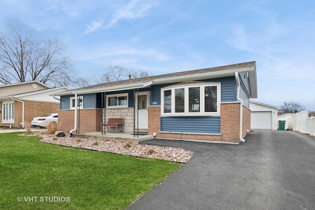 ranch-style home featuring a front lawn, driveway, an outdoor structure, and brick siding
