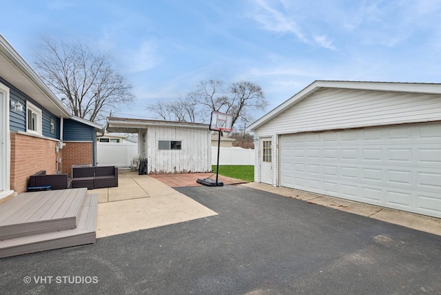 view of patio / terrace featuring an outbuilding, fence, and a garage