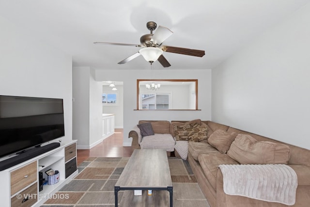 living area featuring wood finished floors and ceiling fan with notable chandelier