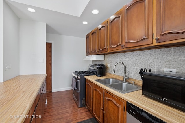 kitchen featuring backsplash, a sink, under cabinet range hood, stainless steel appliances, and dark wood-style flooring
