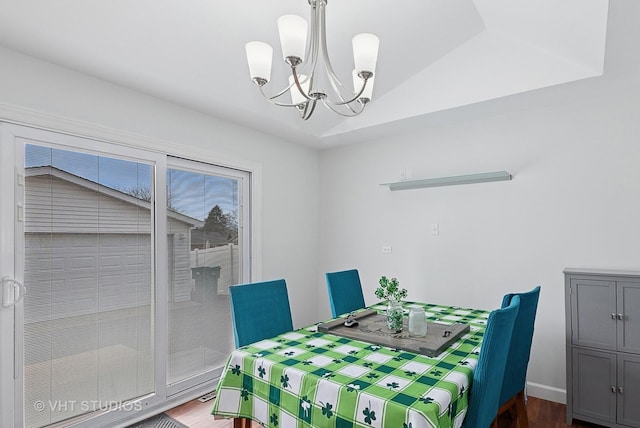 dining space featuring a notable chandelier, vaulted ceiling, and wood finished floors