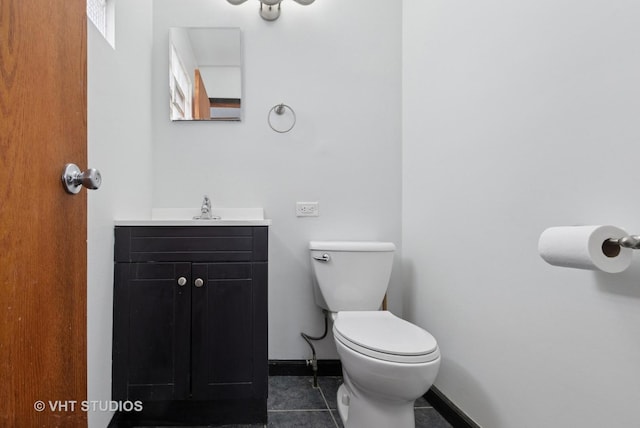 bathroom with toilet, vanity, tile patterned floors, and baseboards