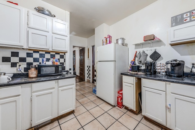 1317 N Harding Ave, Chicago, IL 60651 - kitchen featuring freestanding refrigerator, black microwave, tasteful backsplash, light tile patterned floors, and dark countertops